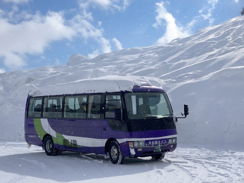 Nagano Snow Shuttle bus parked in the snow on a sunny day